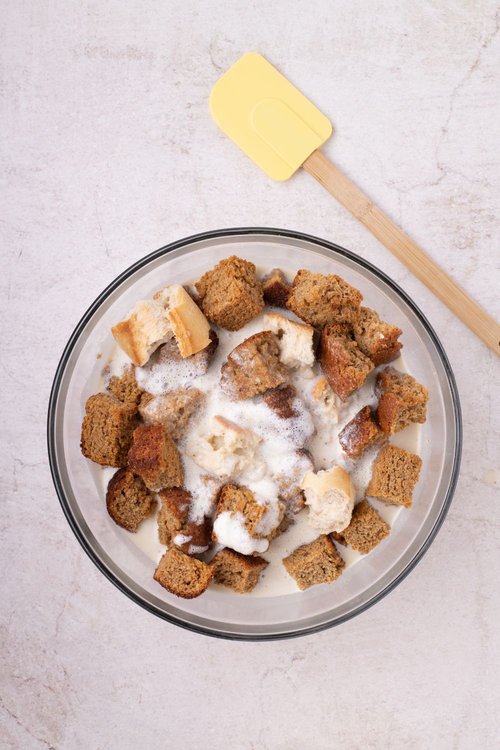bread with the custard mixture in a glass bowl on table