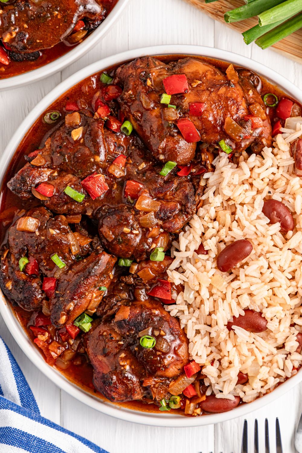 Jamaican Brown Stew Chicken on plate with rice and beans on the side