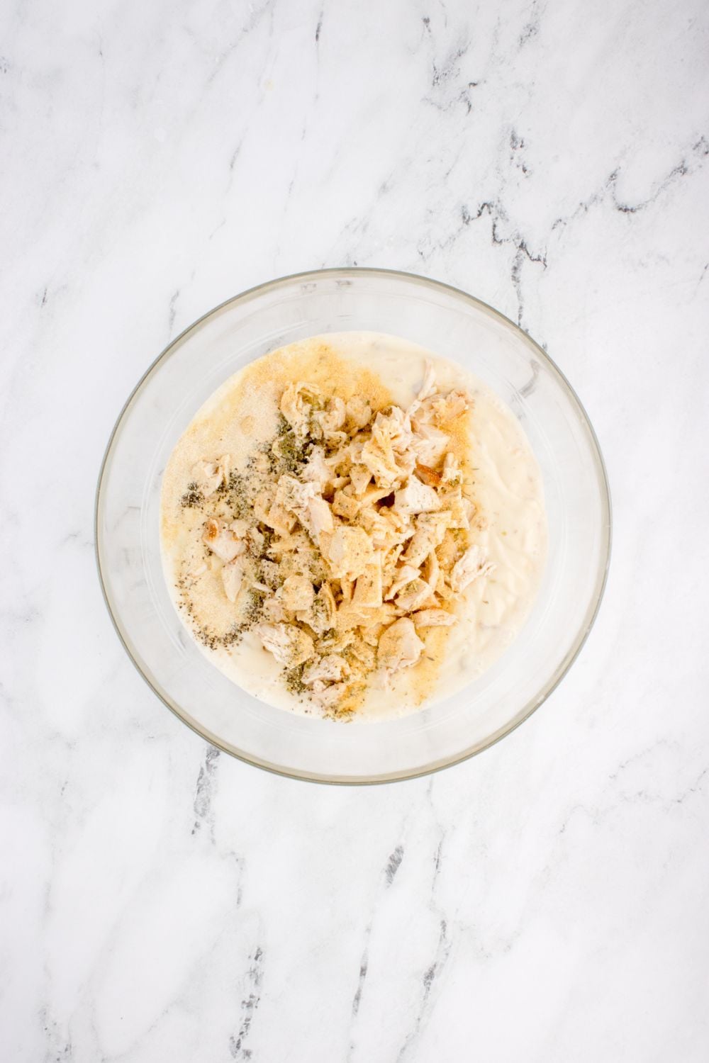 chicken and other ingredients in glass bowl for chicken tetrazzini on table