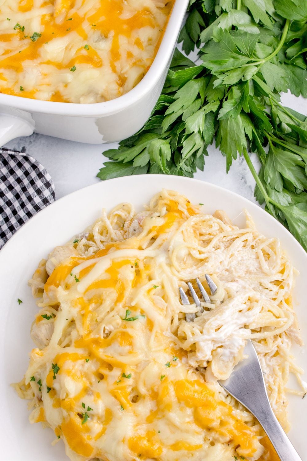 Chicken Tetrazzini on a plate with more in a casserole dish behind it on table