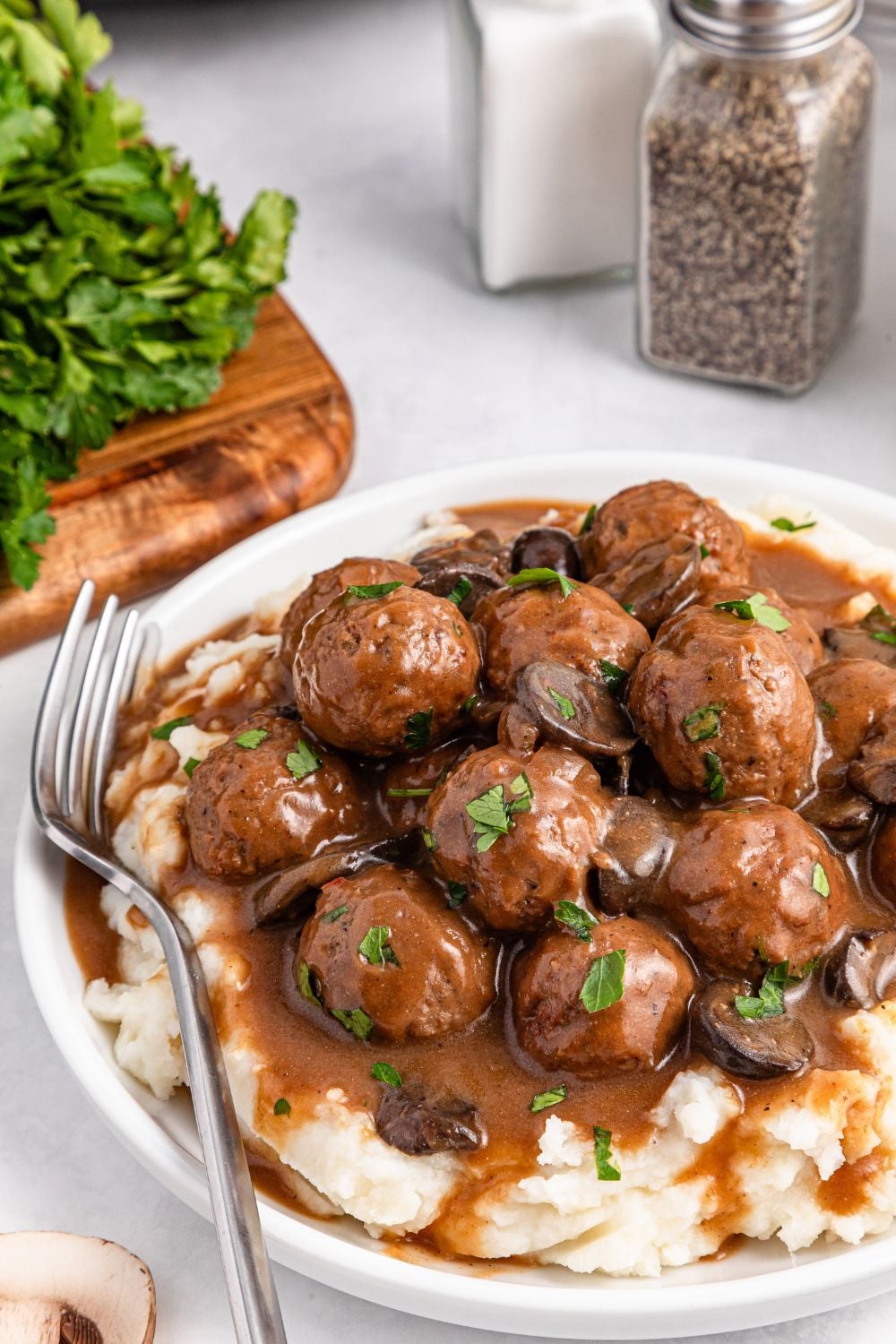Salisbury Steak Meatballs with mashed potatoes under them on a plate with a fork to the side