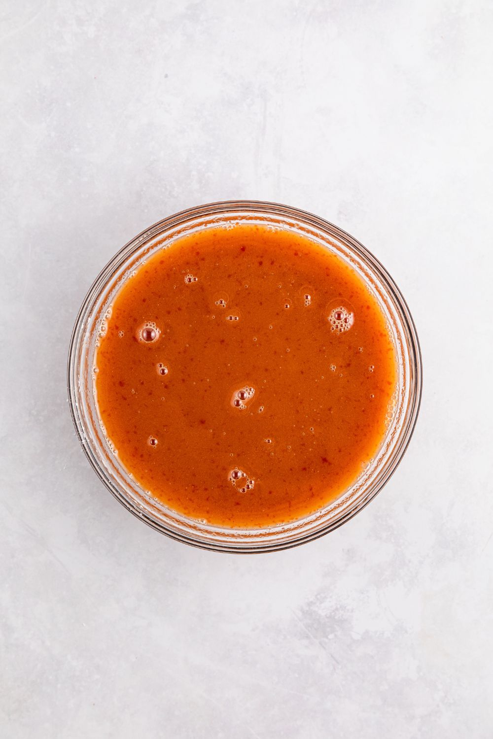 sweet and sour meatball sauce sitting on table in a glass bowl