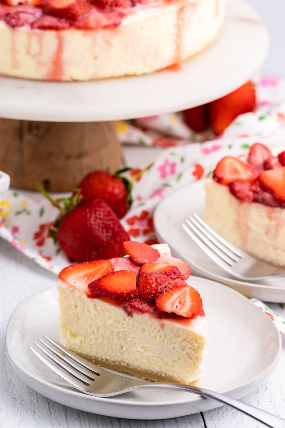 Keto Cheesecake on a platter with slice of cheesecake on the table around it 