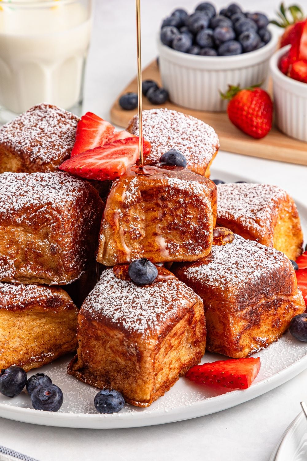 Hawaiian Roll French Toast getting syrup drizzled on top of it on a platter on table 