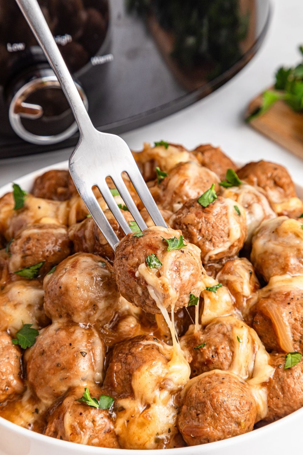 Crock Pot French Onion Meatballs in a bowl with a fork poked into one
