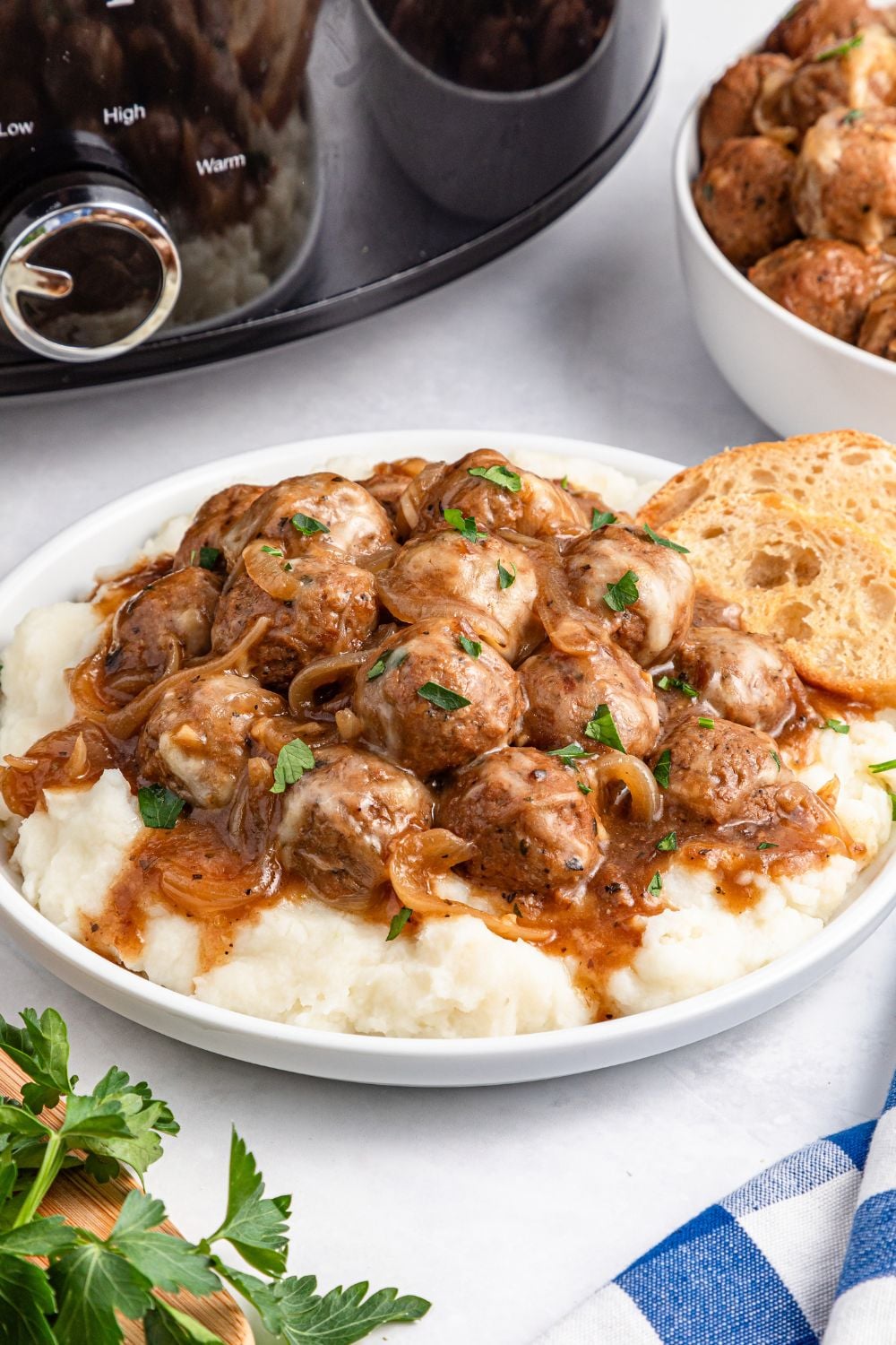 plate with mashed potatoes topped with meatballs, and a bread on side of plate
