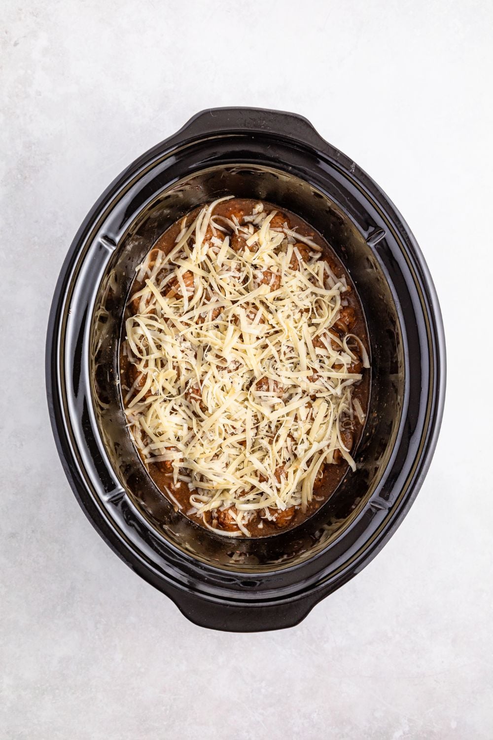 cheese topped French onion meatball mixture in a crock pot