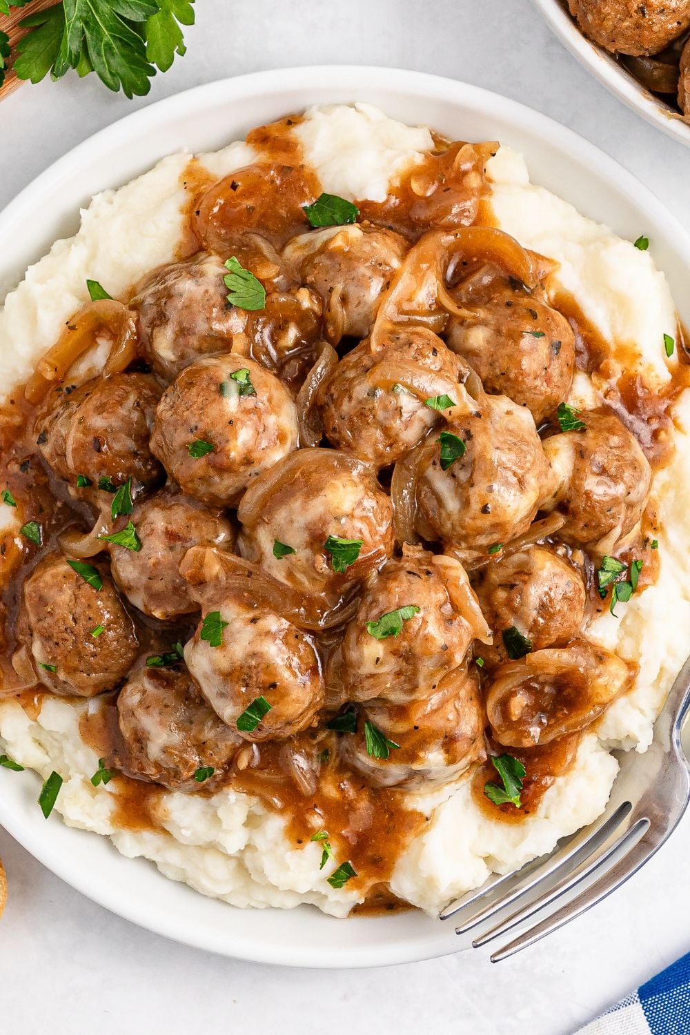 Crock Pot French Onion Meatballs on topped of mashed potatoes on a plate
