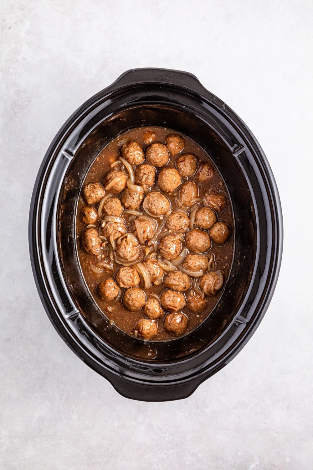 meatballs smothered in a French onion flavored sauce in a crockpot on table