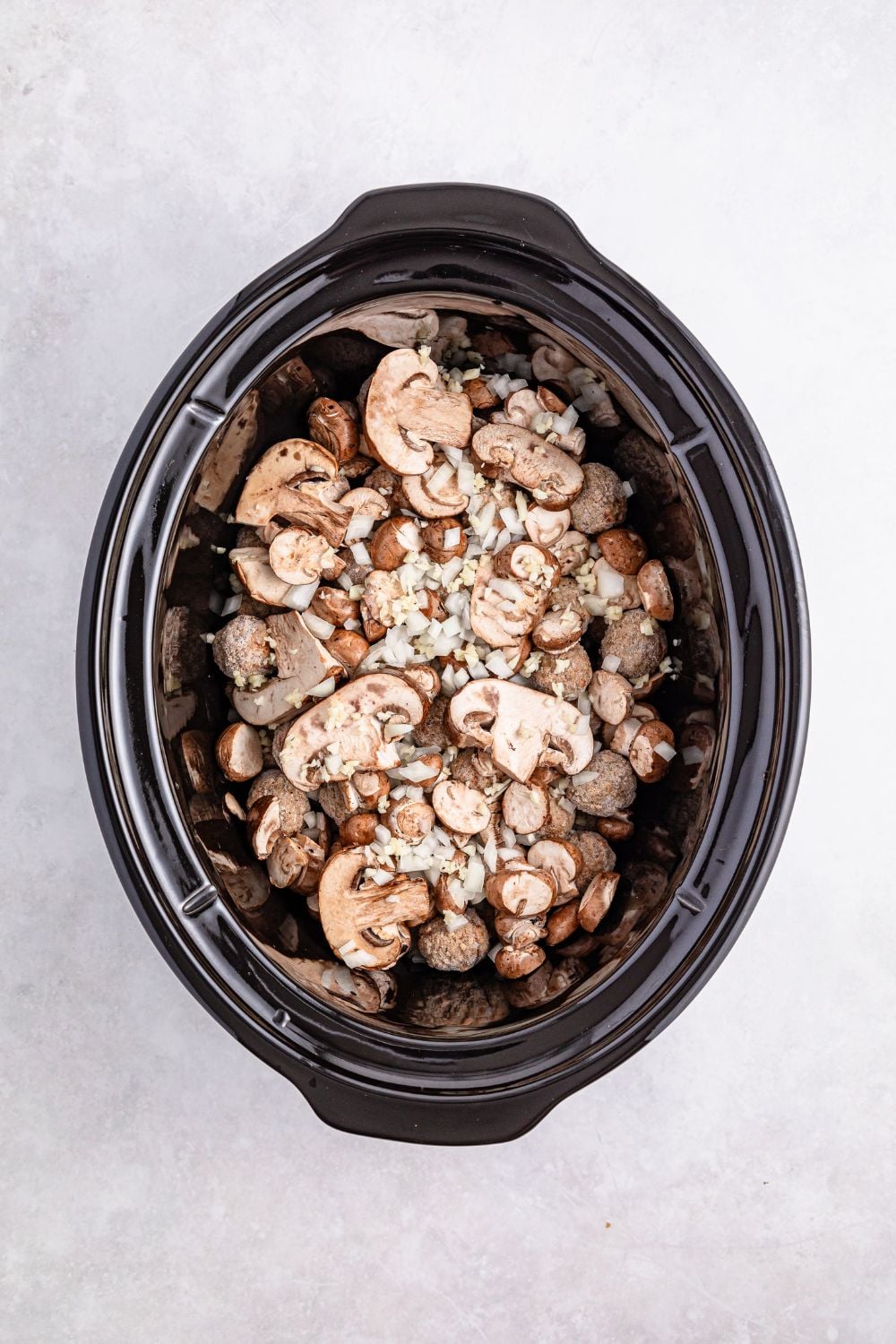 mushrooms and frozen meatballs in a crockpot on the table