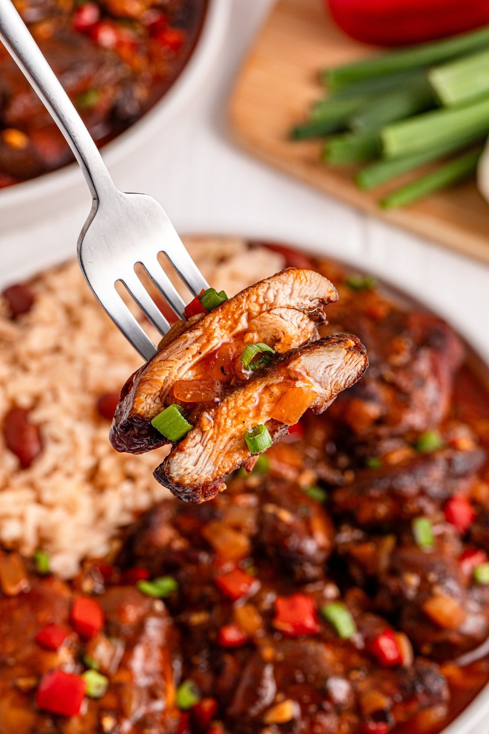 Jamaican Brown Stew Chicken on plate with a fork and a few pieces of chicken on it