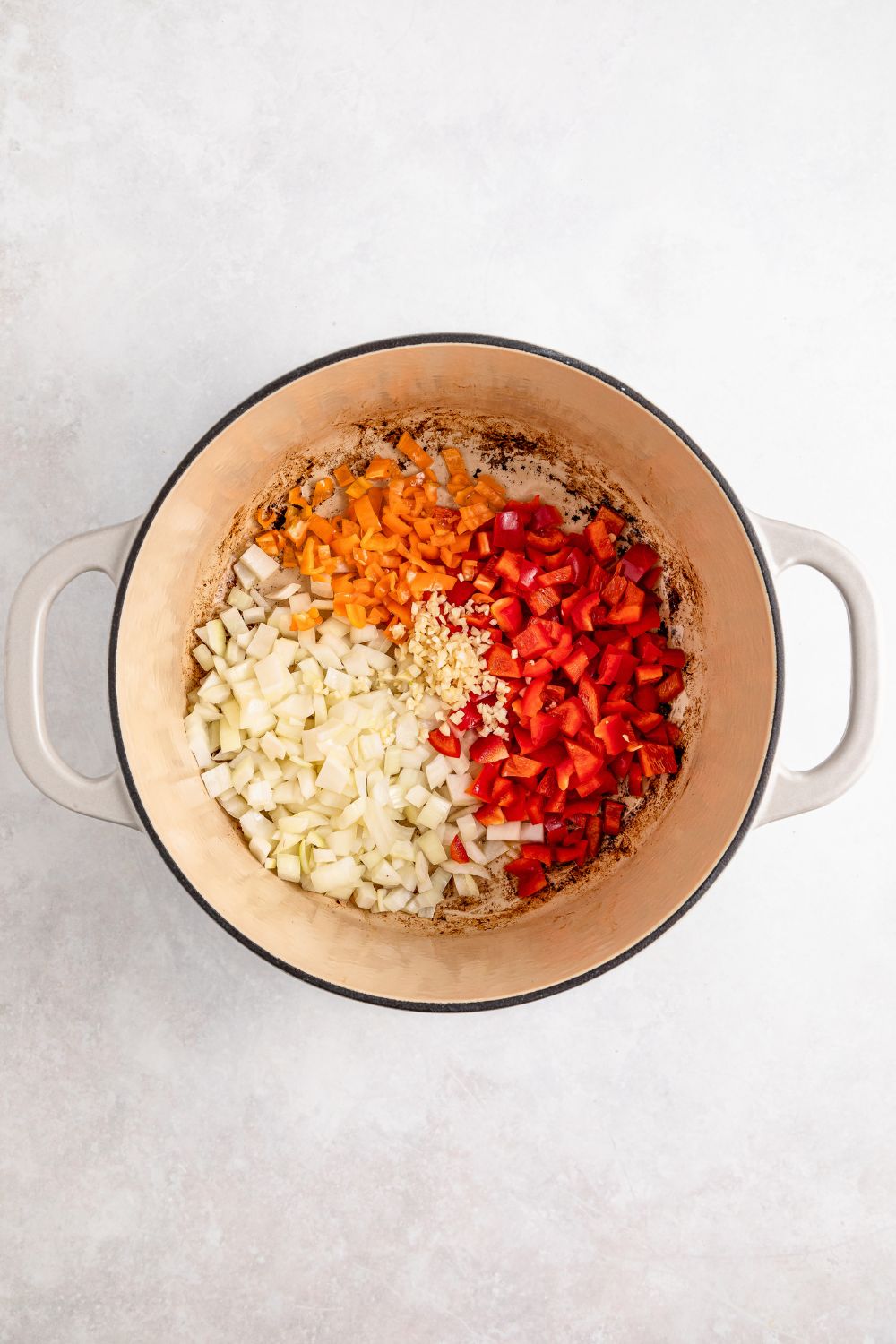 raw diced veggies in a Dutch Oven for Jamaican Brown Stew Chicken