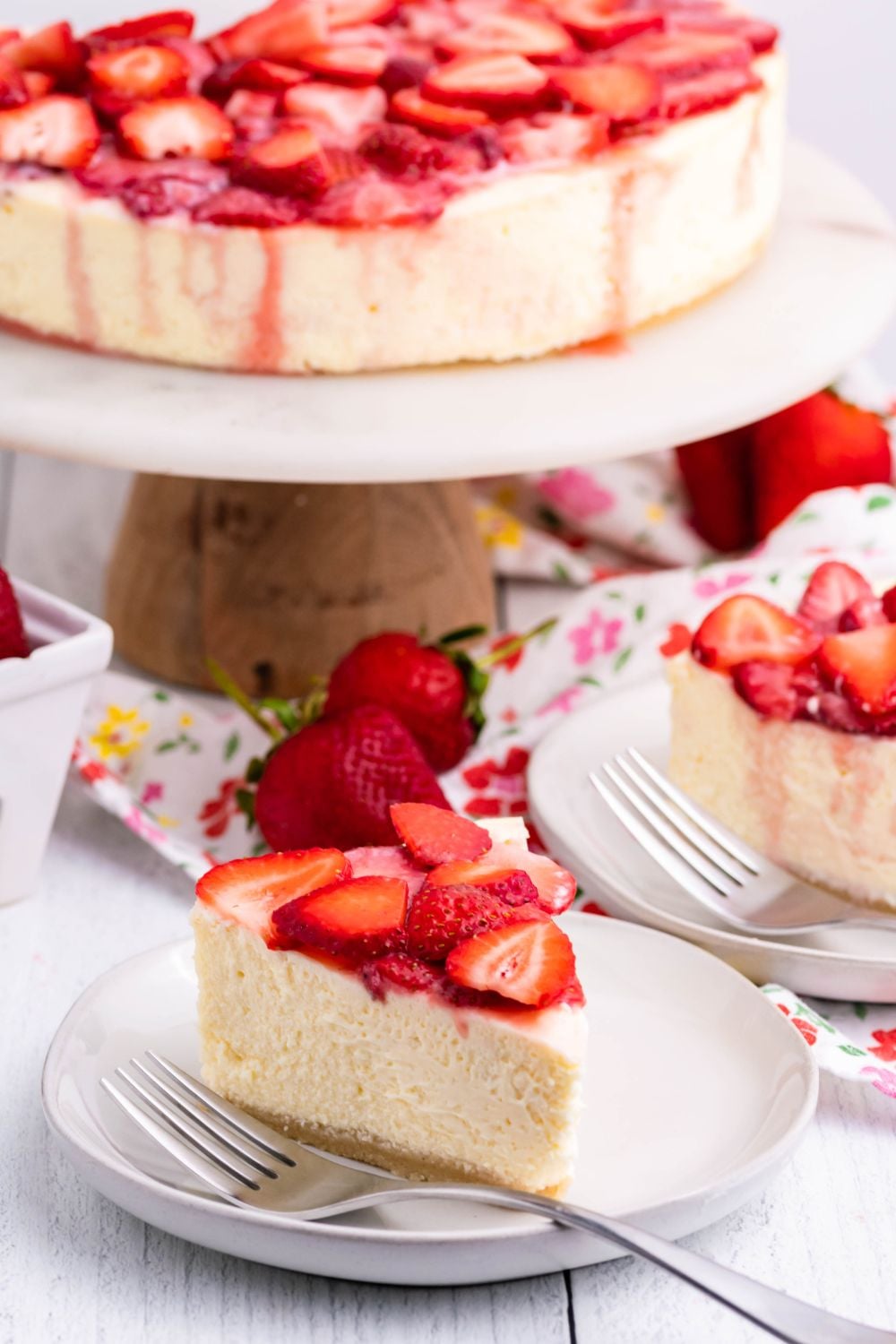 Keto Cheesecake on a pie platter and slices of cheesecake on small plates with berries on top 