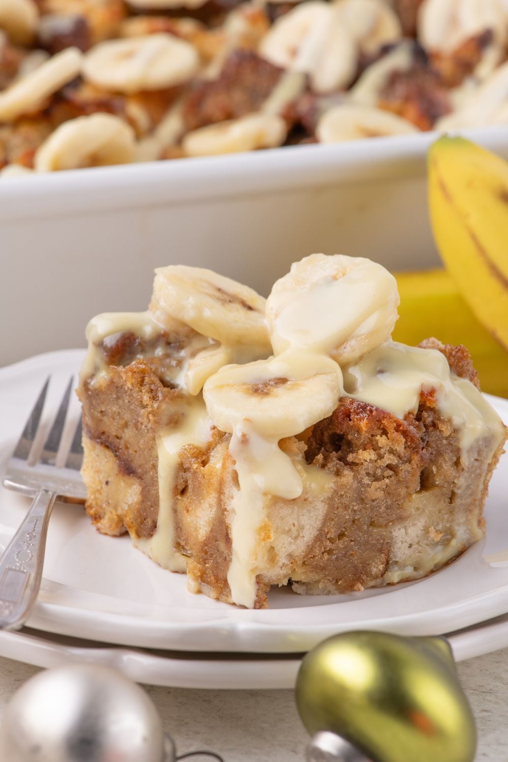double stacked plate with a slice of Banana Bread Pudding on it with a fork on the side