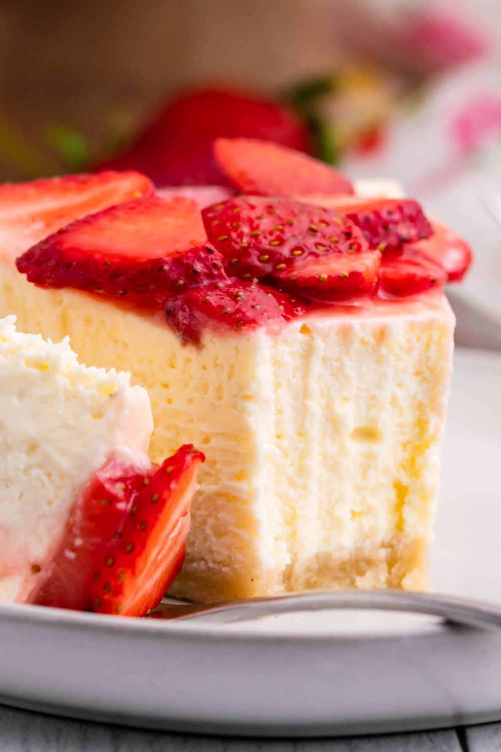 Slice of Keto Cheesecake on a plate with a bite being placed on fork to show the dense texture of cheesecake 