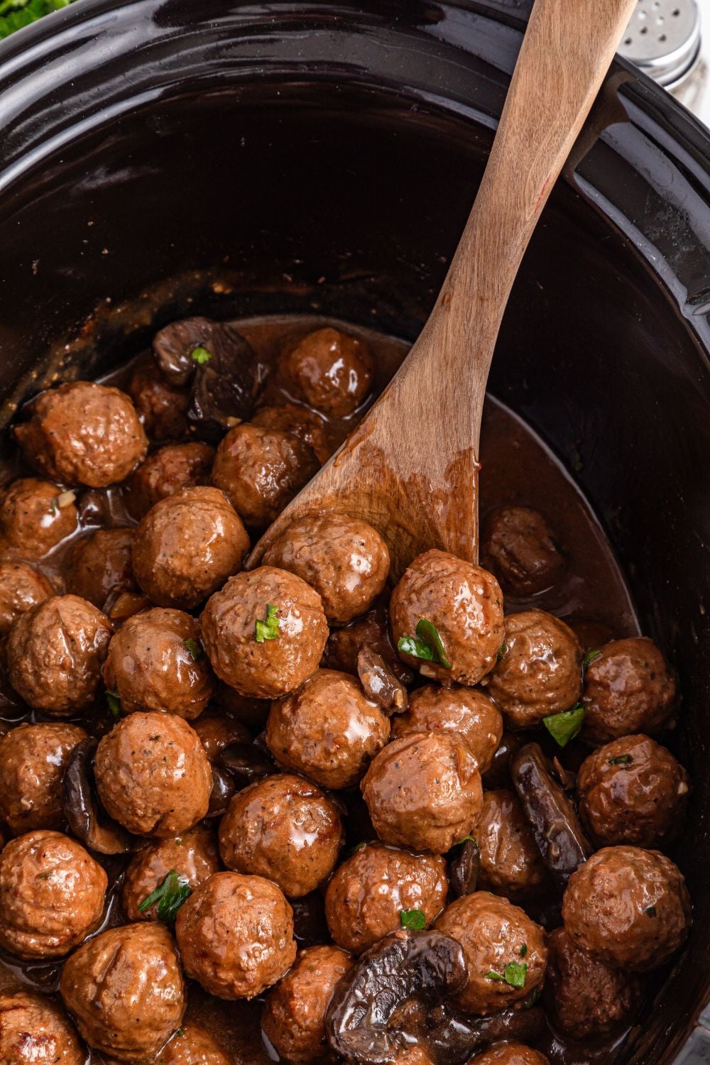 Crock Pot Salisbury Steak Meatballs in the crock pot with a wooden spoon stuck in the pan