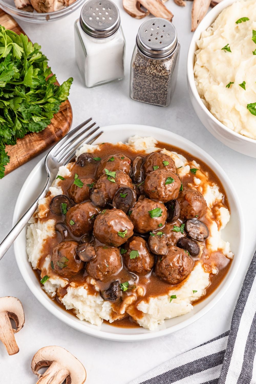 Crock Pot Salisbury Steak Meatballs on a plate with mashed potatoes under them with a fork on the side