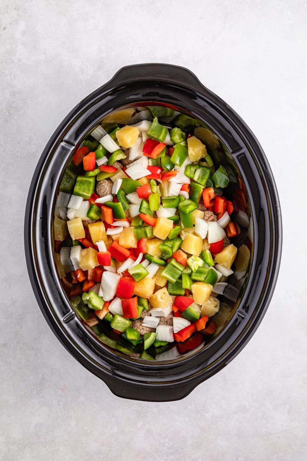 diced peppers and onions in a slow cooker on table for the Crock Pot Sweet And Sour Meatball recipe