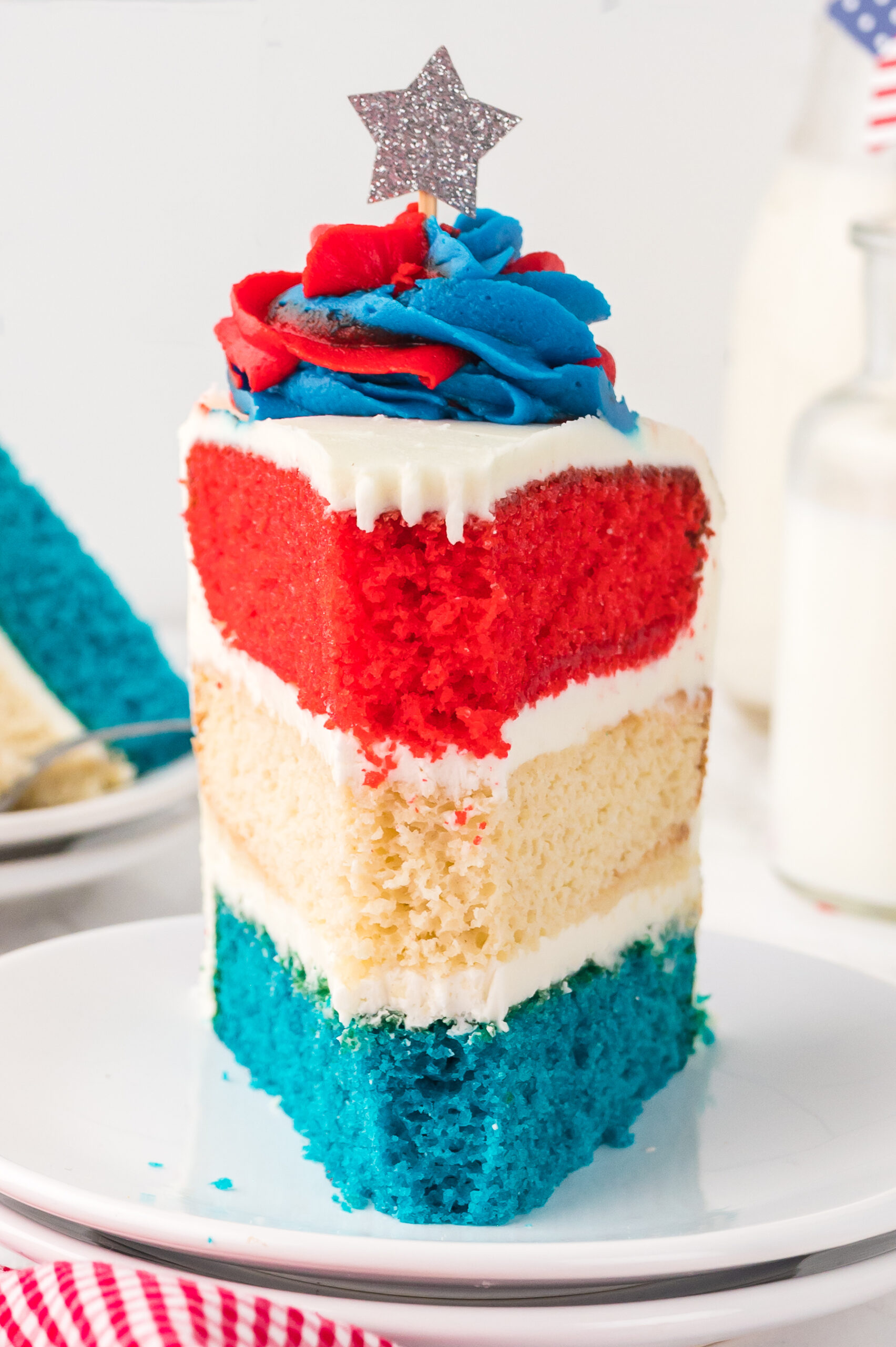 front view of a Slice of American Flag Layered Cake on a white plate with a bite missing