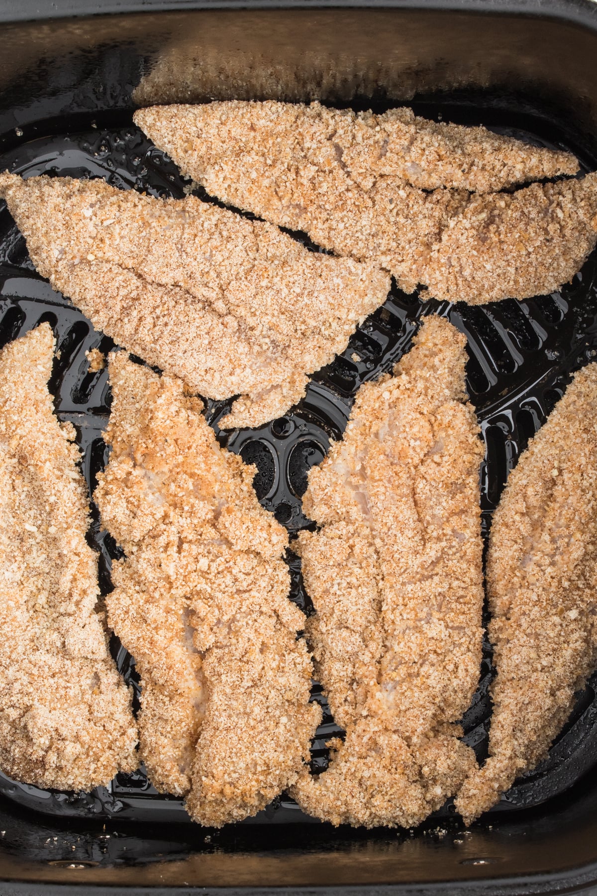 Air Fryer Chicken Tenders uncooked arranged in the air fryer basket