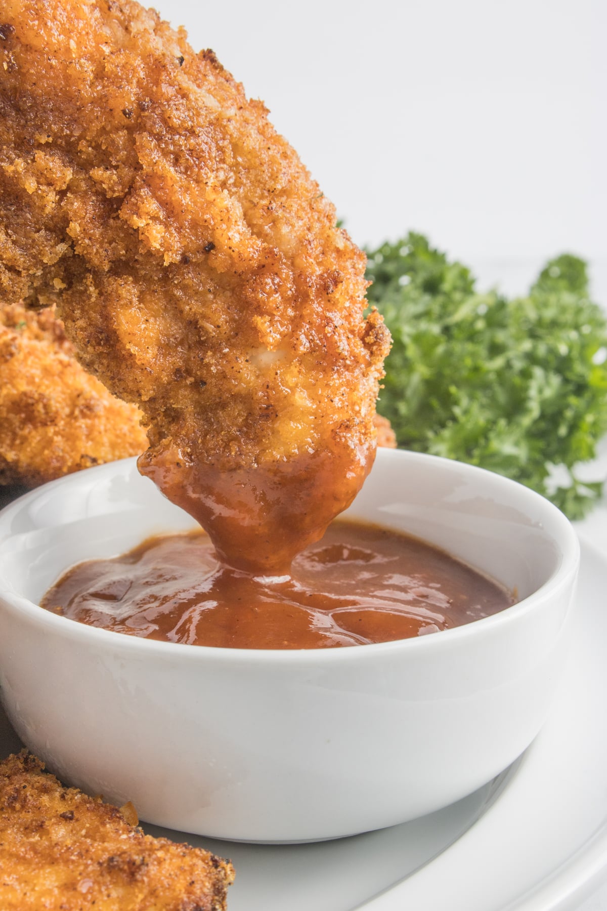 Air Fryer Chicken Tender being dipped into a cup of BBQ sauce