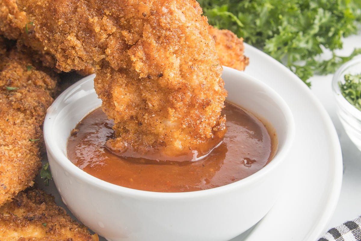 up close shot of Air Fryer Chicken Tender being dipped into BBQ sauce