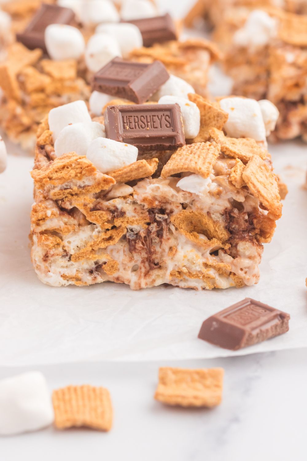S’mores Rice Krispy Treats cut into squares and placed on table with some dry cereal in front of bars 