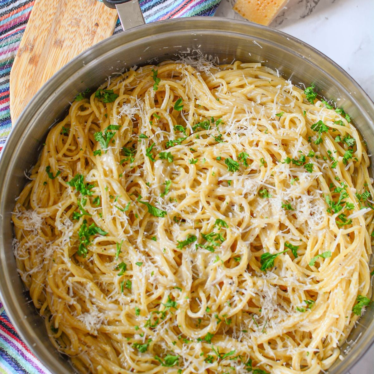 Garlic Parmesan Pasta in a skillet on table with wooden spatula to side