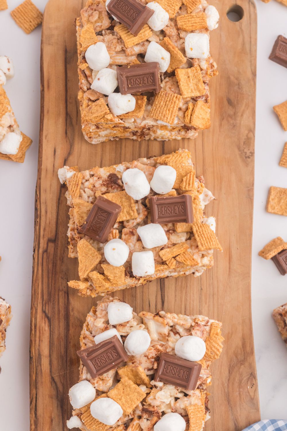 overhead view of S’mores Rice Krispy Treats on a wooden tray with marshmallows around the table 