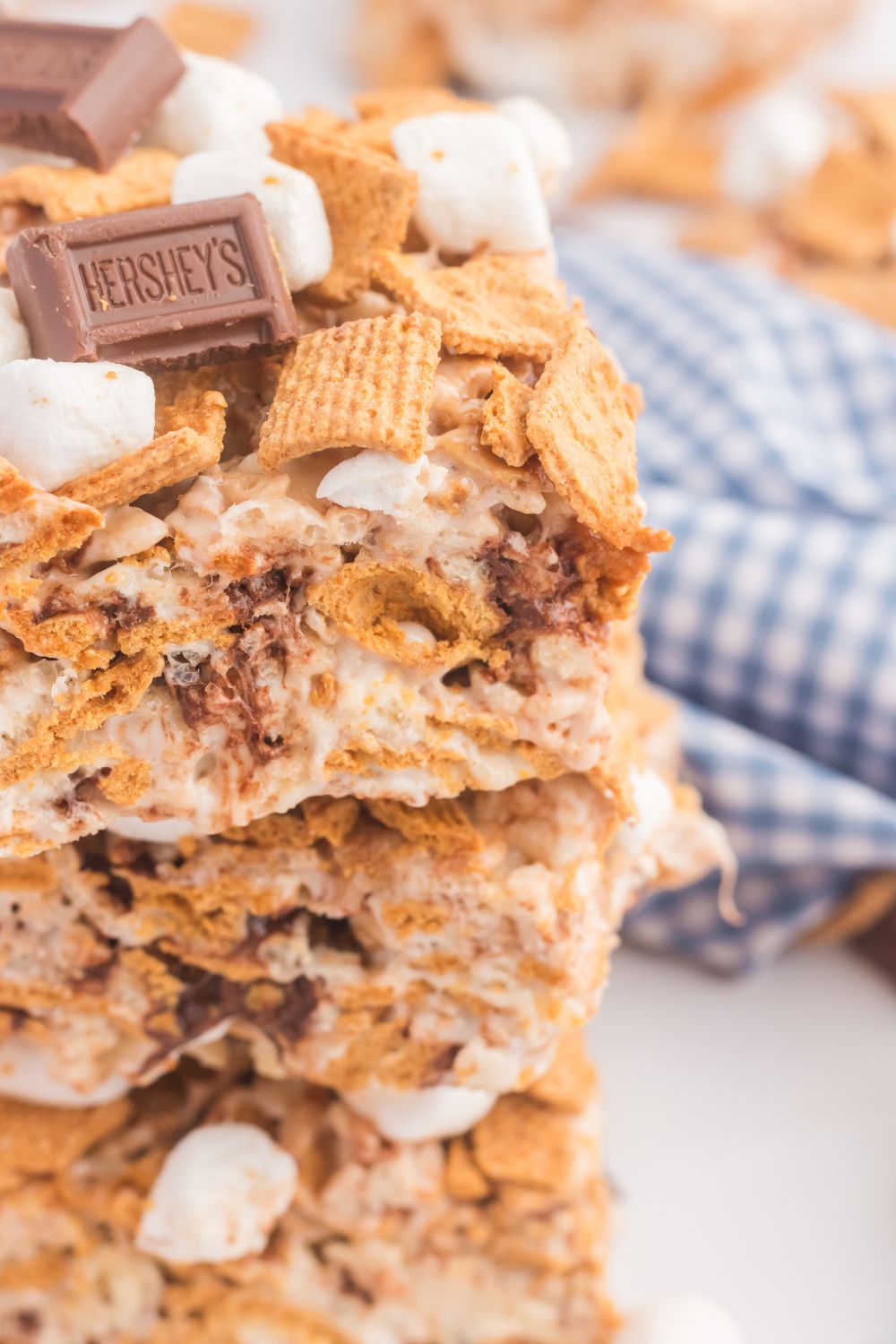 stacked S’mores Rice Krispy Treats on table with a blue checkered napkin behind it 