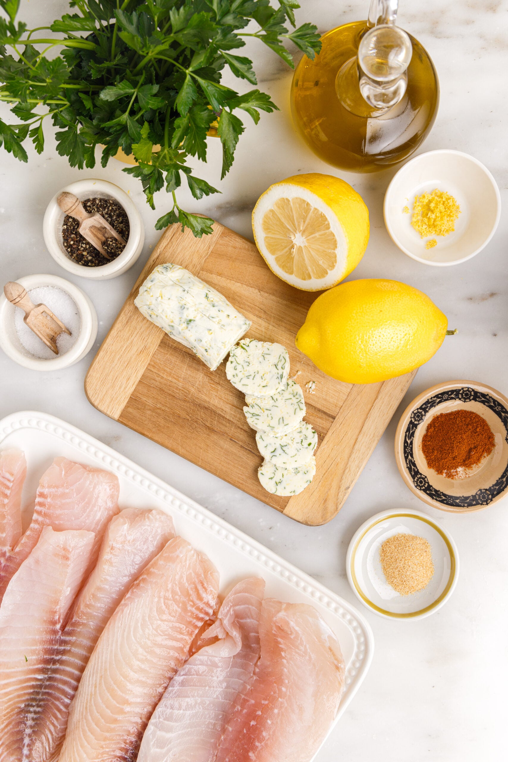 Pan fried tilapia ingredients on a white marble table laid out