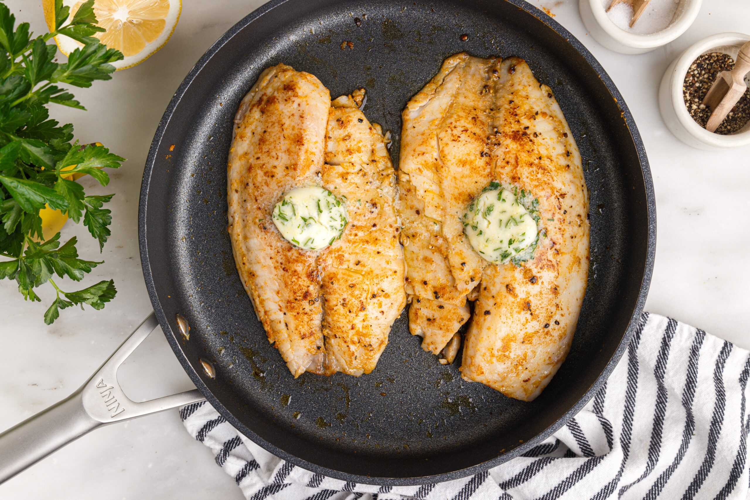 overhead shot of the Pan Fried Tilapia in a skillet up close topped with butter