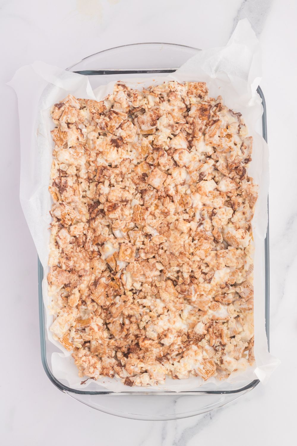 rice crispy treats being made poured in a casserole dish 