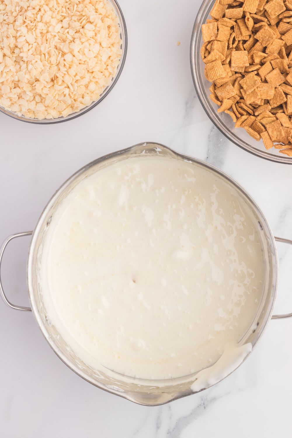 melted marshmallow mixture in a bowl on table with cereal in separate bowls 