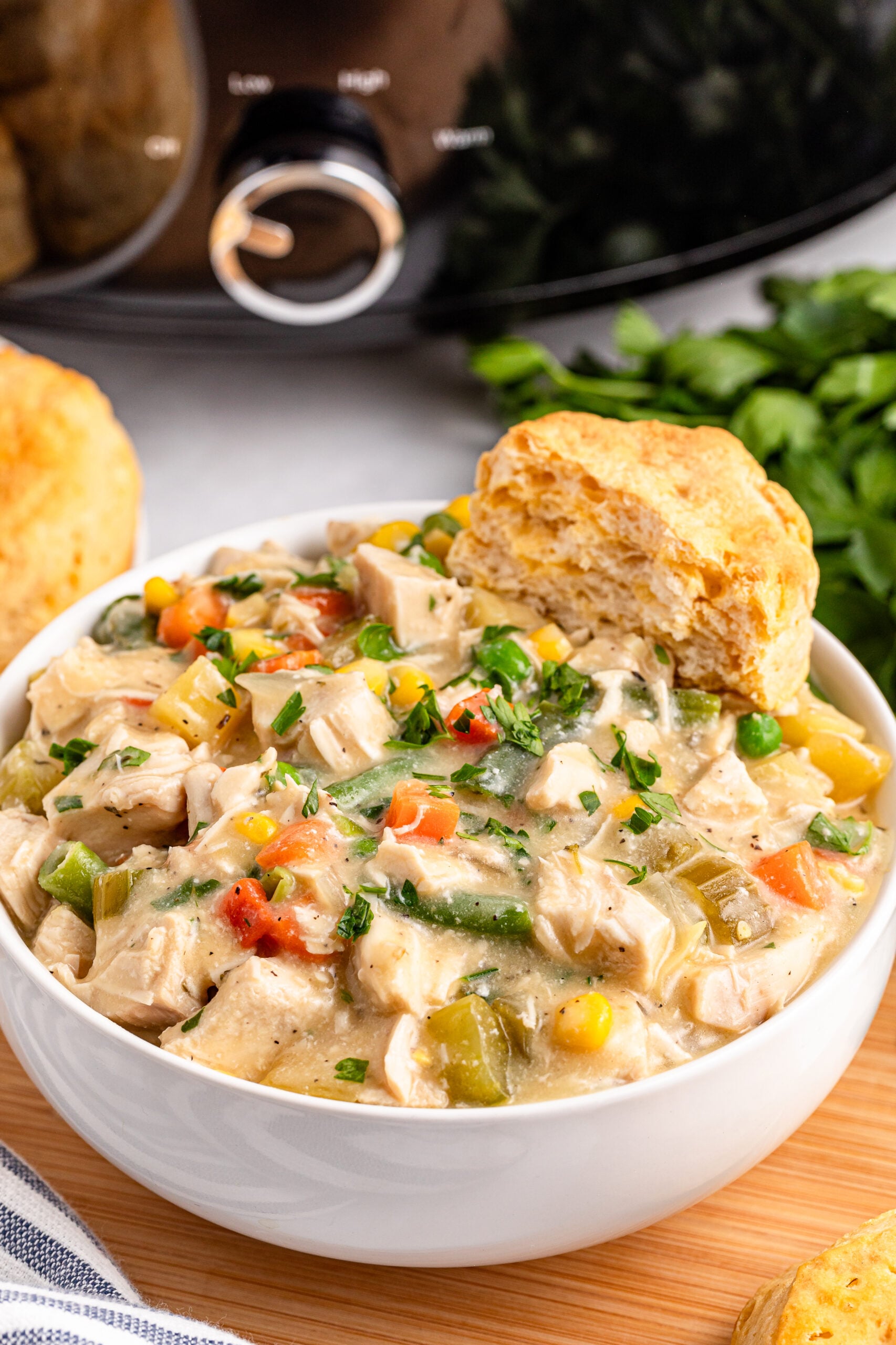 white bowl filled with Slow Cooker Chicken Pot Pie with a biscuit on the side