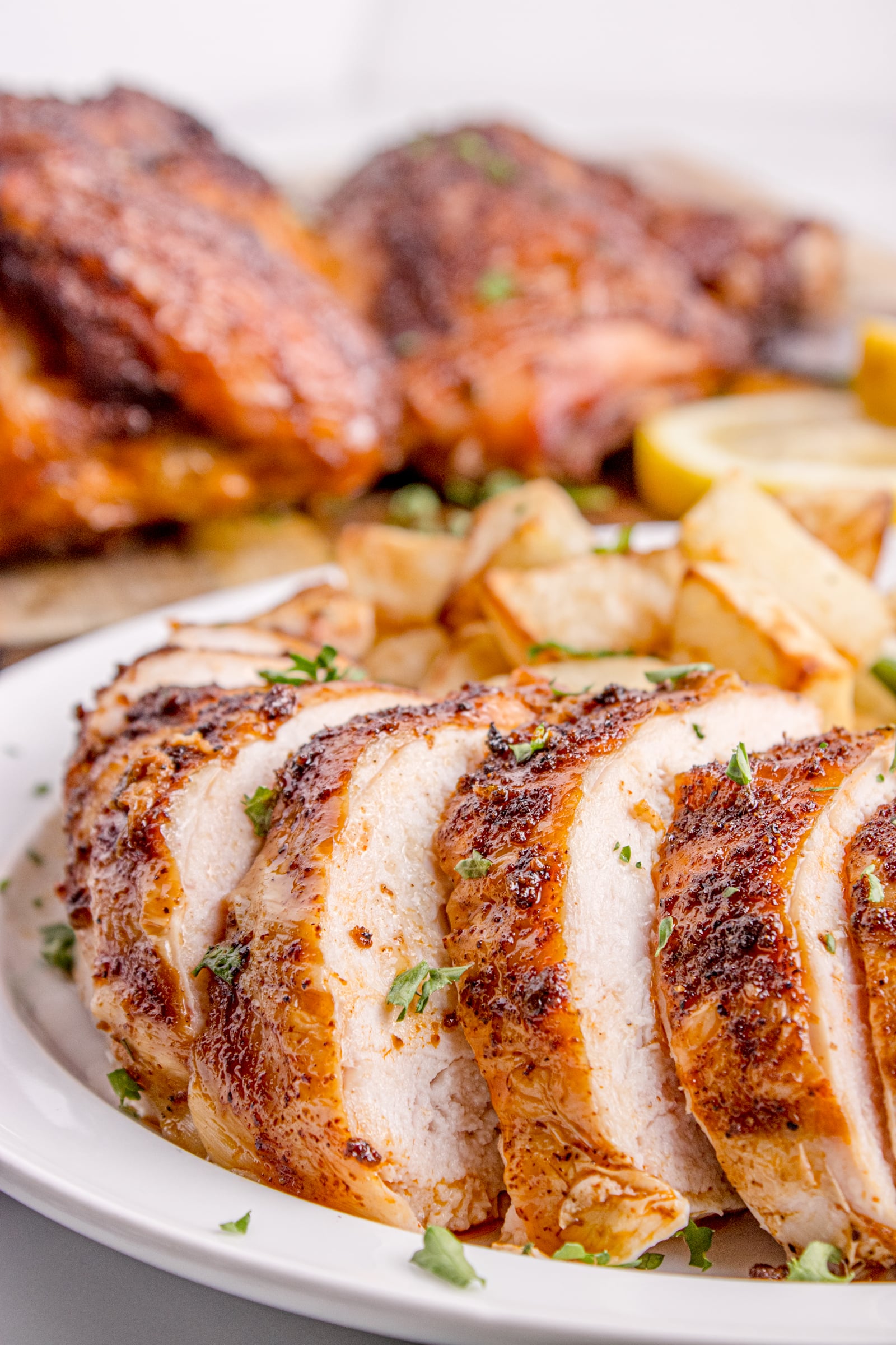 Smoked Whole Chicken on a white plate with some pieces sliced on it