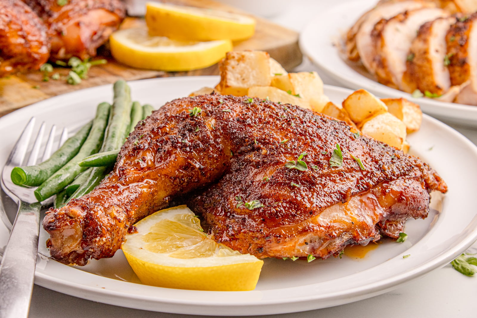 Smoked Whole Chicken leg on a white plate with lemon slices