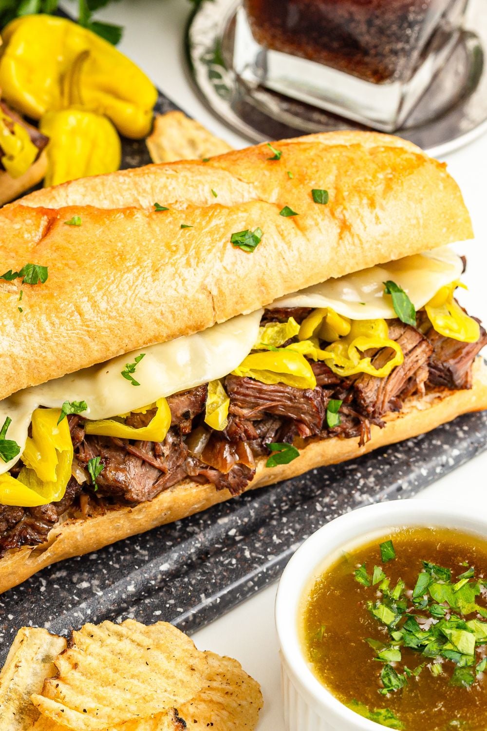 Mississippi Pot Roast Sandwich on table with sauce in a bowl in front 