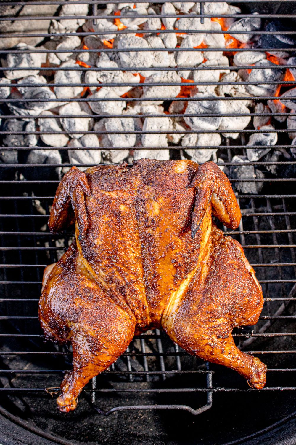 Smoked Whole Chicken sitting on a charcoal grill