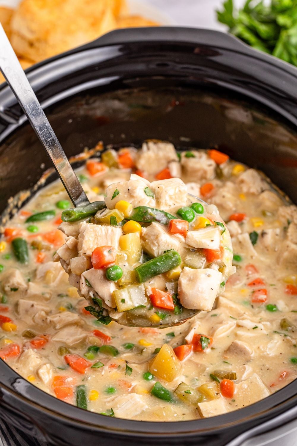 ladle of chicken pot pie mixture in slow cooker being lifted out of slow cooker