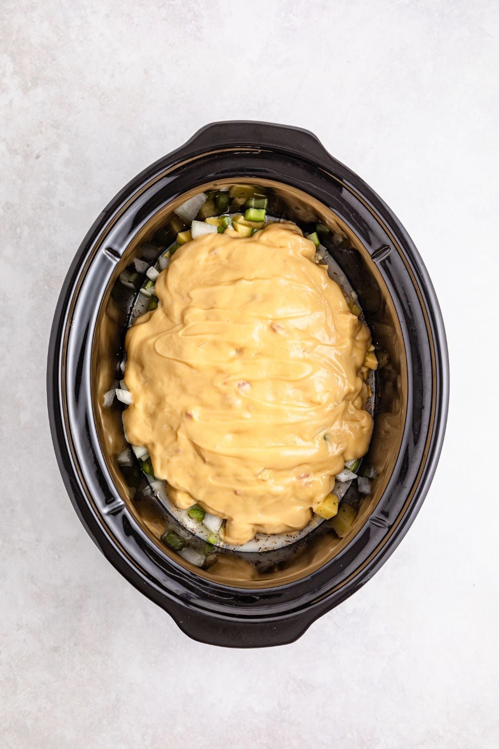 cream of chicken soup poured over veggies in slow cooker on table 