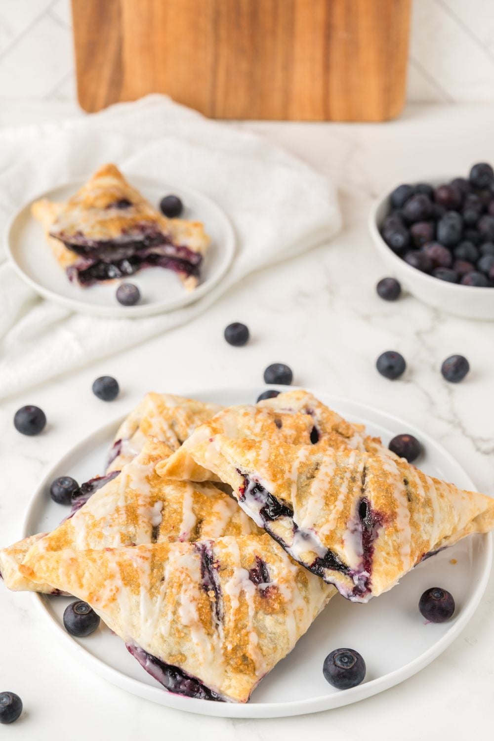 Blueberry Turnovers on a plate with fresh blueberries in a bowl and around the table