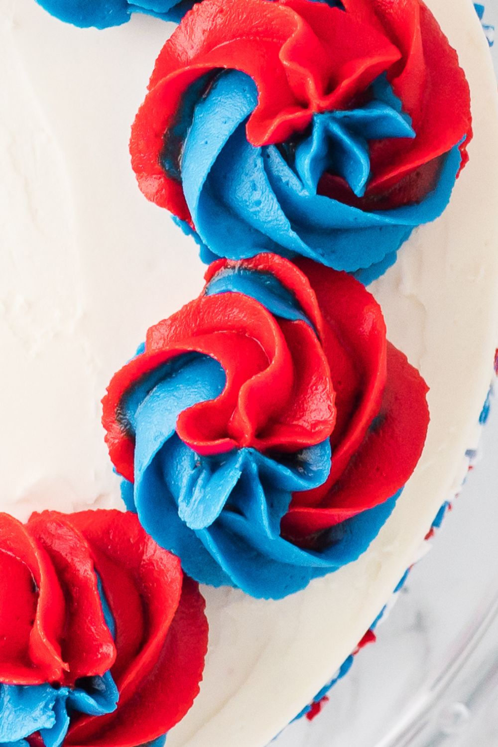 red and blue swirls of frosting piped on top of a cake 