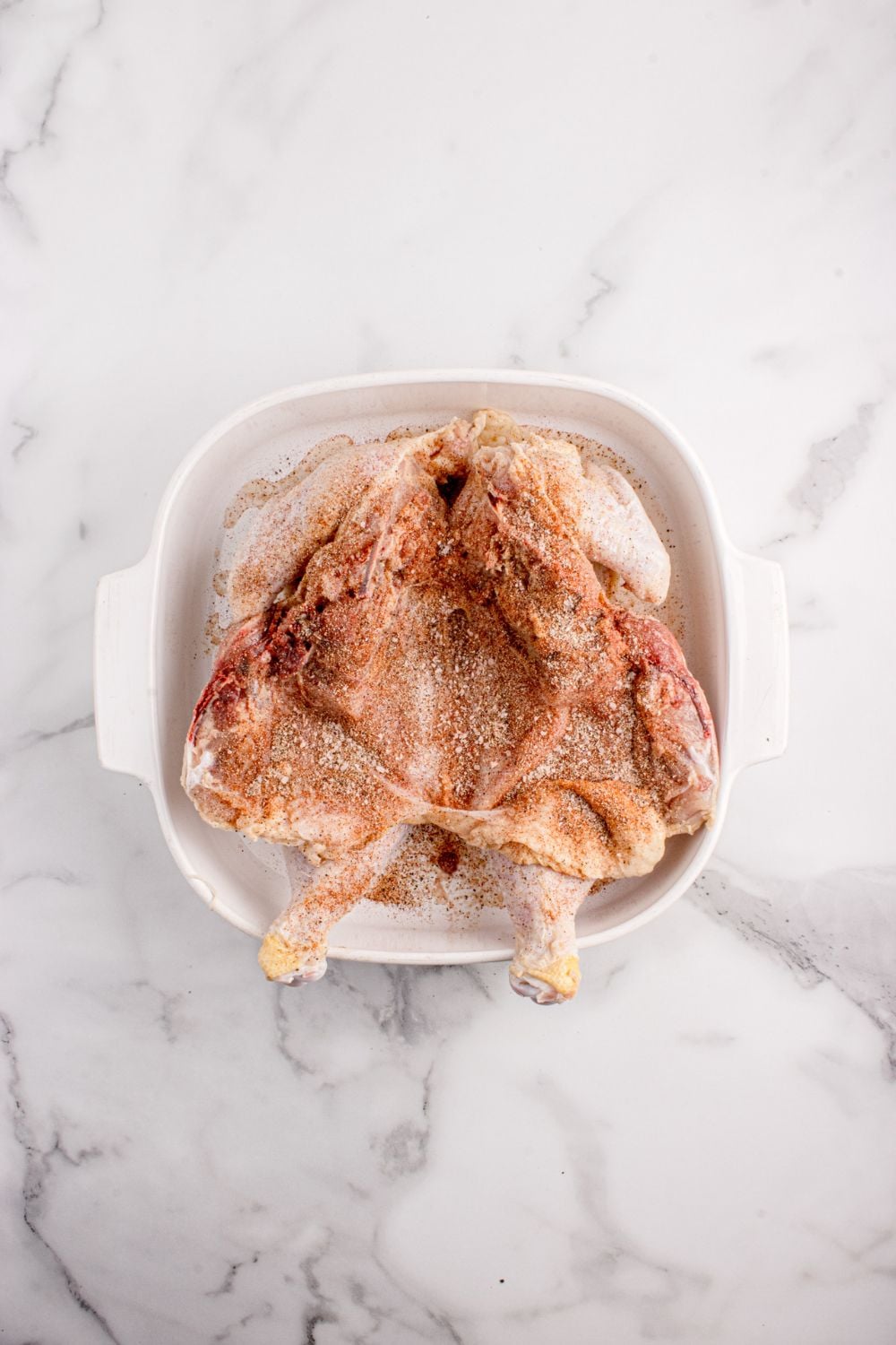 broken down raw chicken seasoned with dry rub