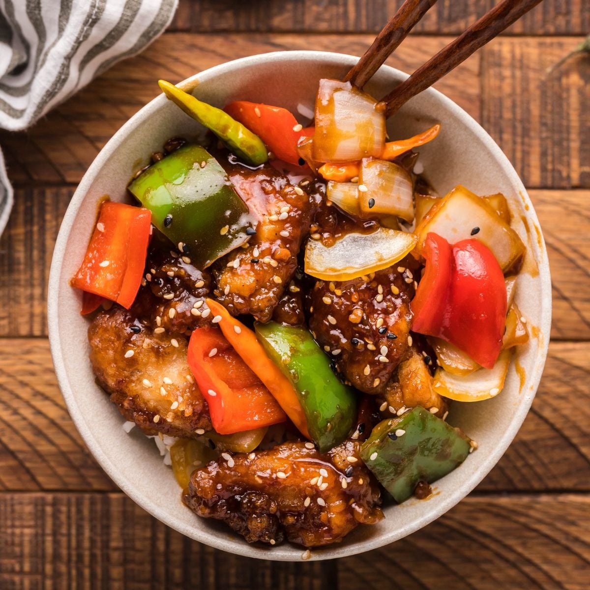 General Tso Chicken in a bowl with tongs on the side