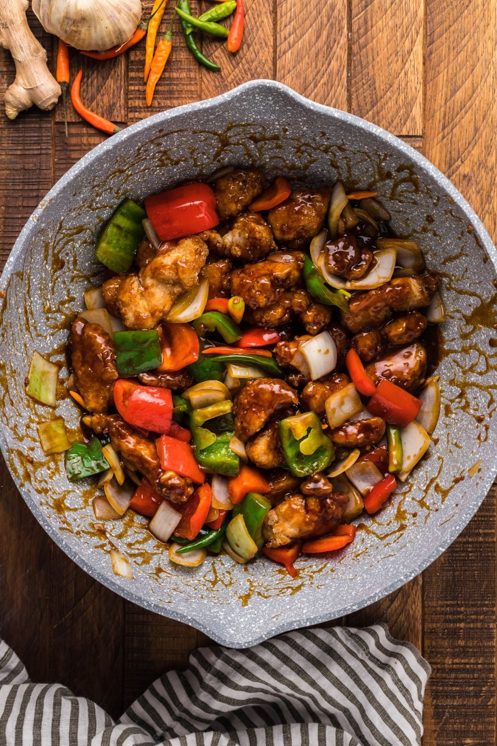 General Tso Chicken being tossed in sauce with veggies in bowl