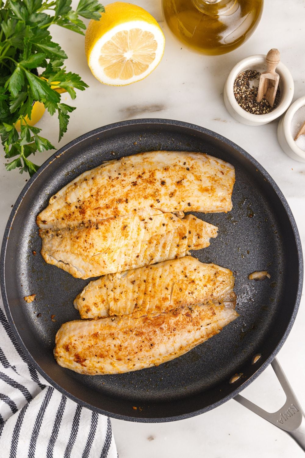 cooked Pan Fried Tilapia in a skillet on table