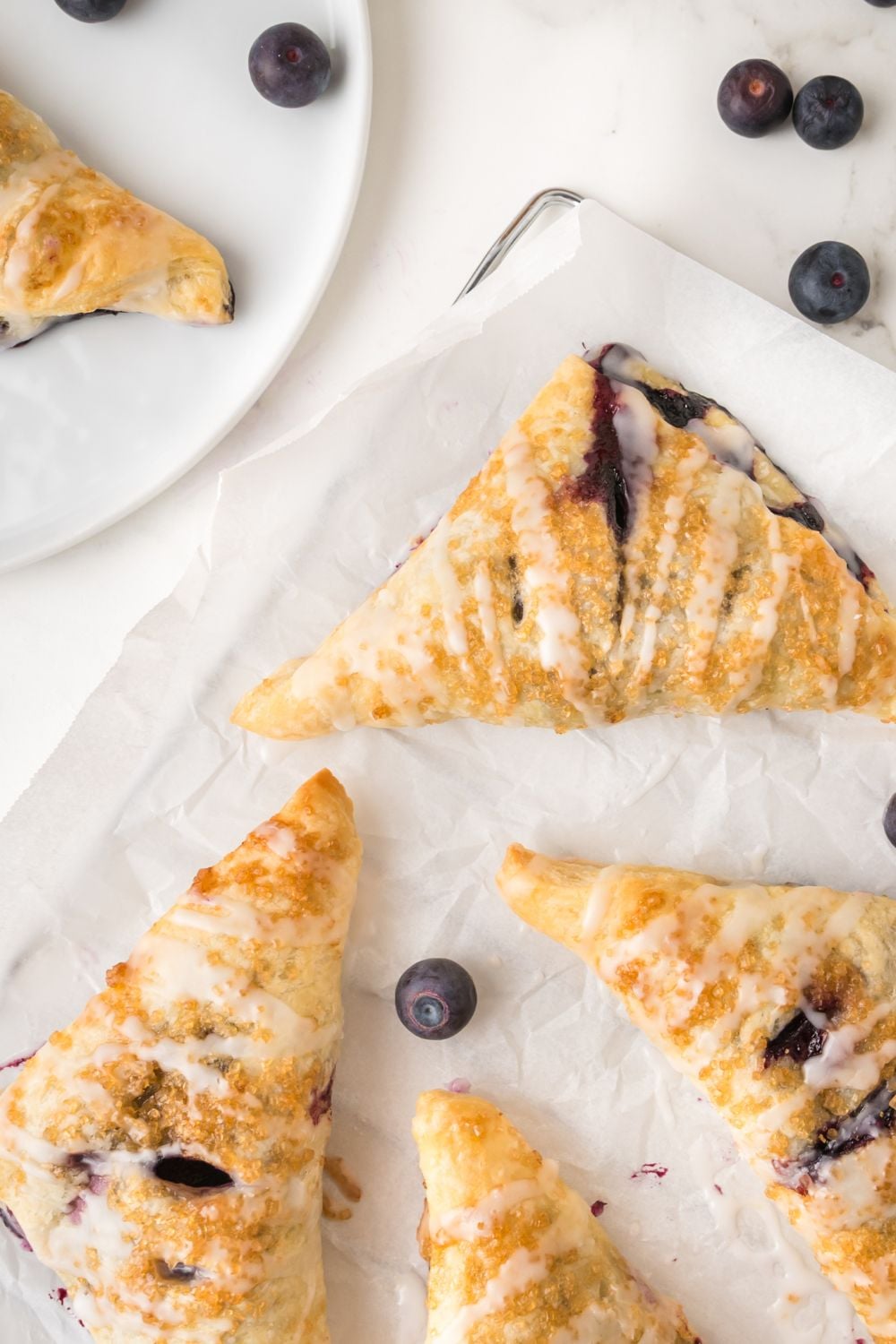 Blueberry Turnovers spread out on sheet pan covered with parchment paper