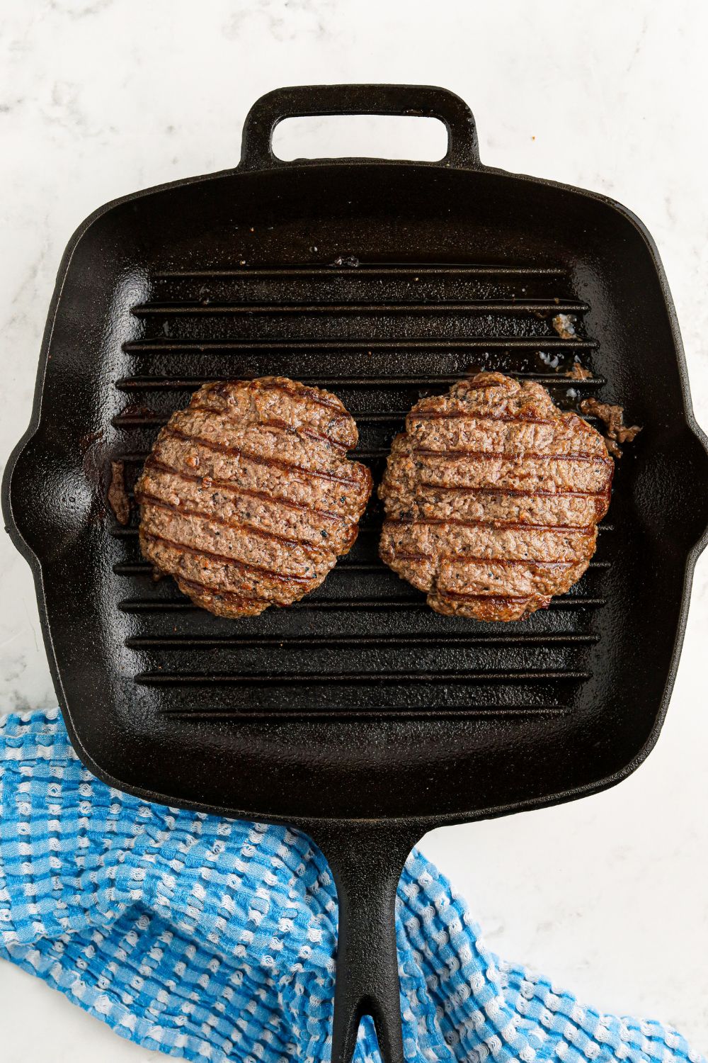 grill pan with cooked hamburgers in pan sitting on table