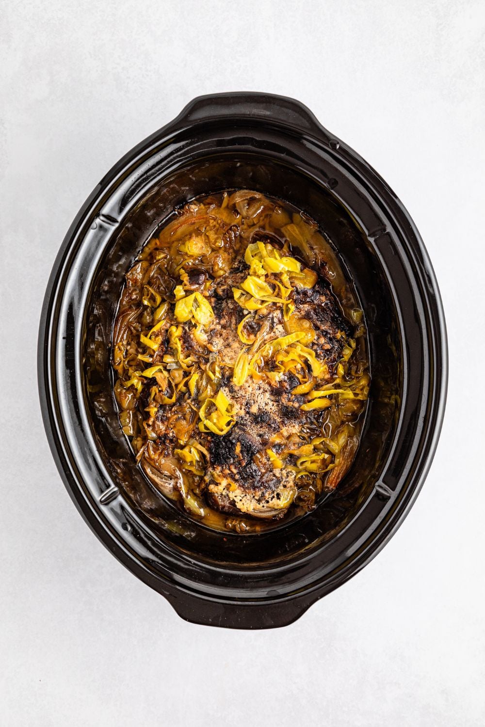 cooked pot roast in slow cooker on table 